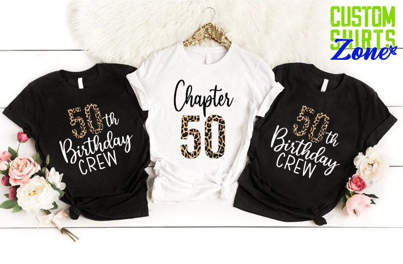 May include: Three black t-shirts with white text and a leopard print design. The shirts say "50th Birthday Crew" and "Chapter 50".
