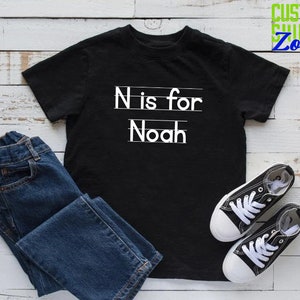May include: Black t-shirt with white text that says "N is for Noah".