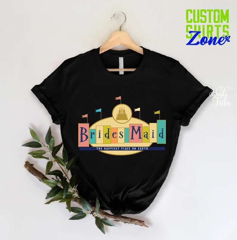 Puede incluir: Camiseta negra con un gr&aacute;fico de un castillo y el texto "Brides Maid" en letras de colores. El texto "The Happiest Place on Earth" est&aacute; debajo del gr&aacute;fico.