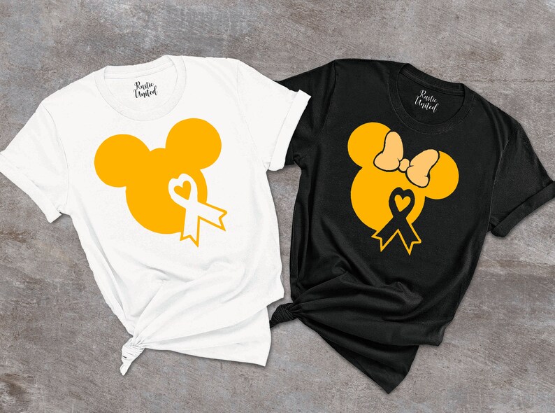 K&ouml;nnte beinhalten: Zwei T-Shirts mit einem gelben Mickey-Maus-Kopf-Design. Der Mickey-Maus-Kopf hat ein gelbes Band mit einem wei&szlig;en Herzen in der Mitte. Ein T-Shirt ist wei&szlig; und das andere ist schwarz. Beide T-Shirts haben den Text "Rustic United" auf der R&uuml;ckseite.
