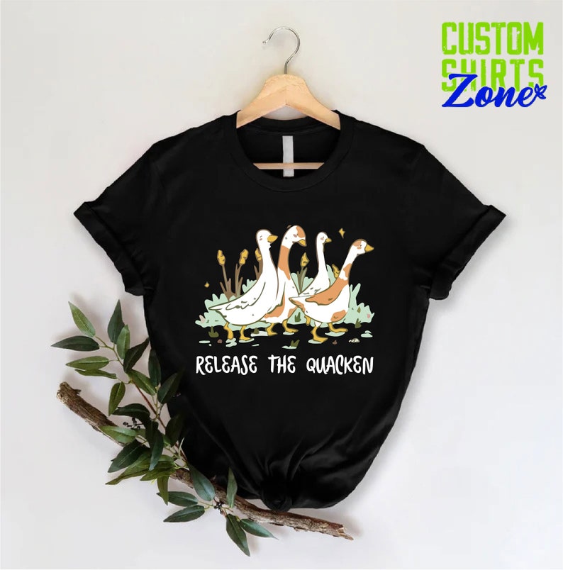 May include: Black t-shirt with a graphic of four geese walking in a line. The text "Release the Quacken" is printed below the geese.