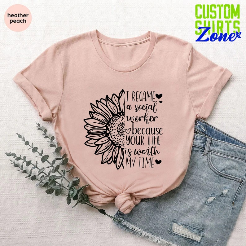 May include: A pink t-shirt with a black sunflower graphic and the text "I became a social worker because your life is worth my time".