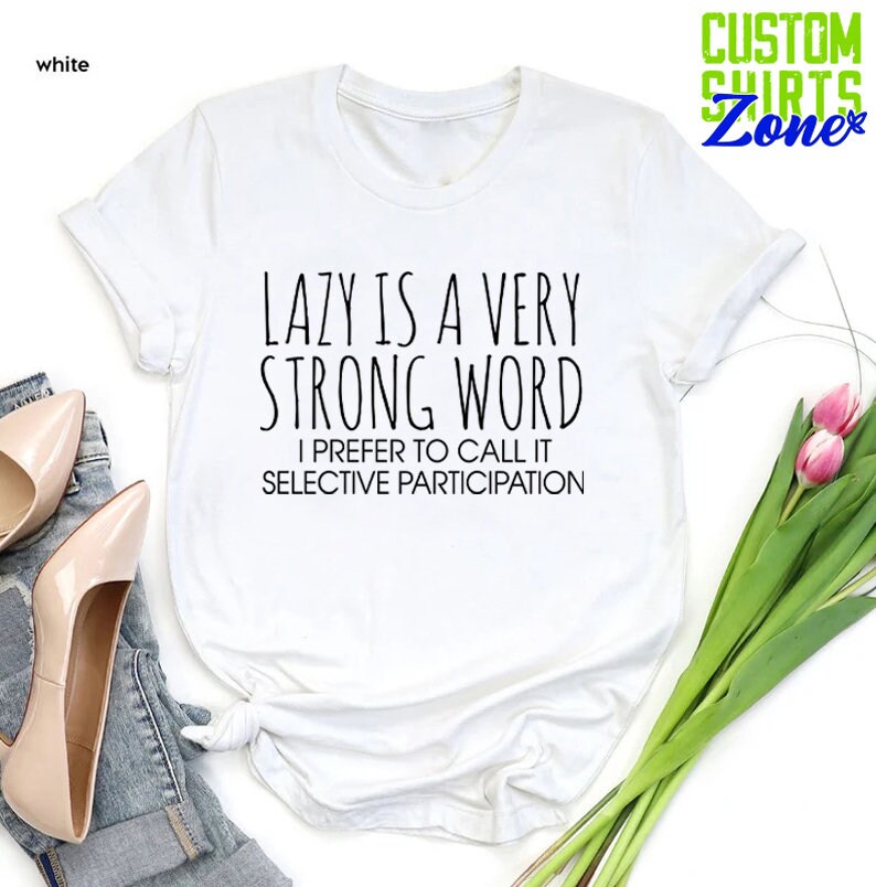 May include: White t-shirt with black text that reads "LAZY IS A VERY STRONG WORD I PREFER TO CALL IT SELECTIVE PARTICIPATION".