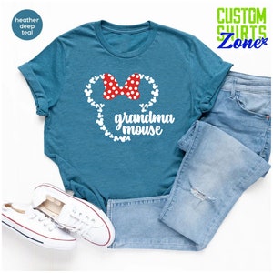 Op de afbeelding: Petrolkleurig T-shirt met een witte muizenkop-afbeelding en een rode stippen strik. De tekst "grandma mouse" staat eronder. Lichtblauwe jeans en witte sneakers maken de casual look compleet. Het shirt is van Custom Shirts Zone.