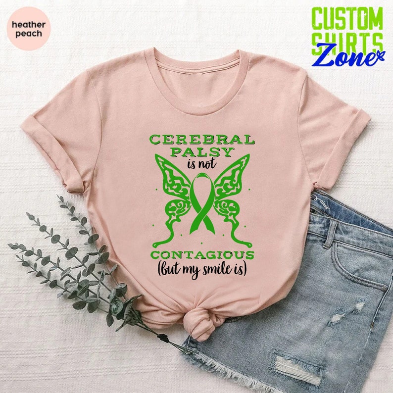 May include: A pink t-shirt with a green butterfly graphic and the text "Cerebral Palsy is not contagious (but my smile is)".
