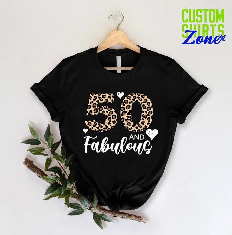 K&ouml;nnte beinhalten: Schwarzes T-Shirt mit einer Leopardenmuster-Nummer 50 und dem Text "AND Fabulous" in Wei&szlig;.