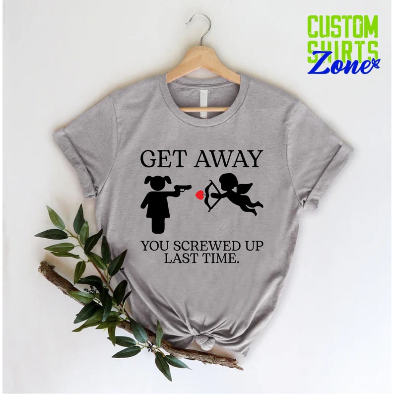 May include: Gray t-shirt with a black graphic of a woman pointing a gun at a cupid with the text "Get Away You Screwed Up Last Time."
