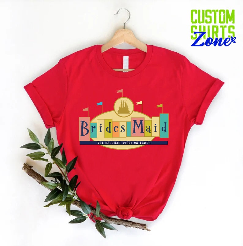 Puede incluir: Camiseta roja con un gr&aacute;fico de un castillo y el texto "Brides Maid" con las palabras "The Happiest Place on Earth" debajo.