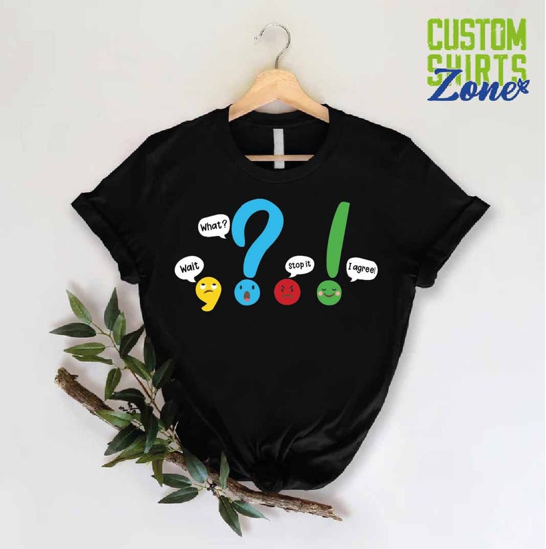May include: Black t-shirt with a graphic of punctuation marks with faces. The punctuation marks are a comma, question mark, exclamation point, and period. The text on the shirt says "Wait", "What?", "Stop it", and "I agree!"