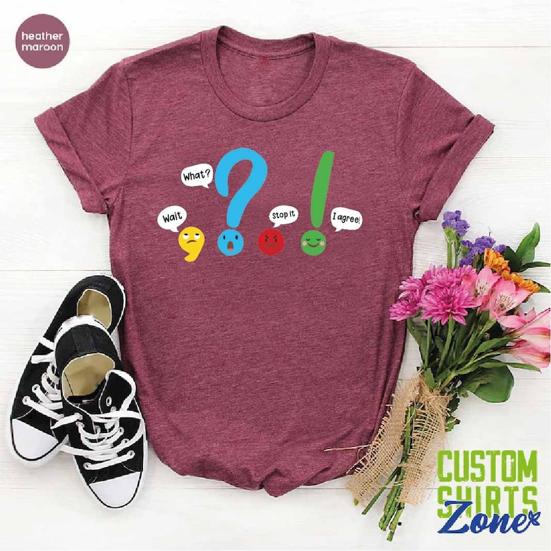 May include: A heather maroon t-shirt with a graphic of punctuation marks with faces and speech bubbles. The text on the shirt reads "Wait", "What?", "Stop it", and "I agree".