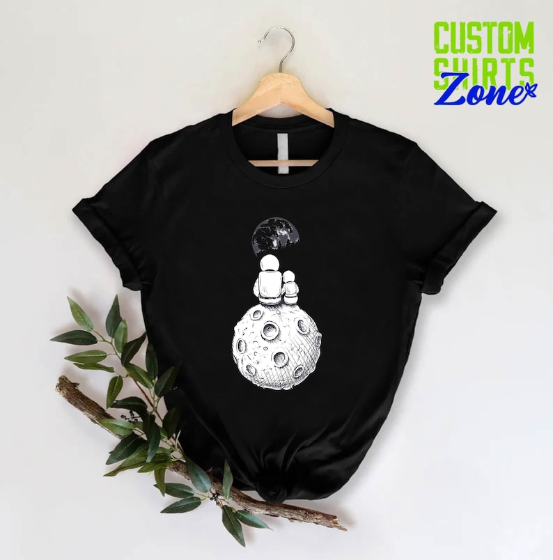 a black t - shirt with a picture of a man sitting on top of a
