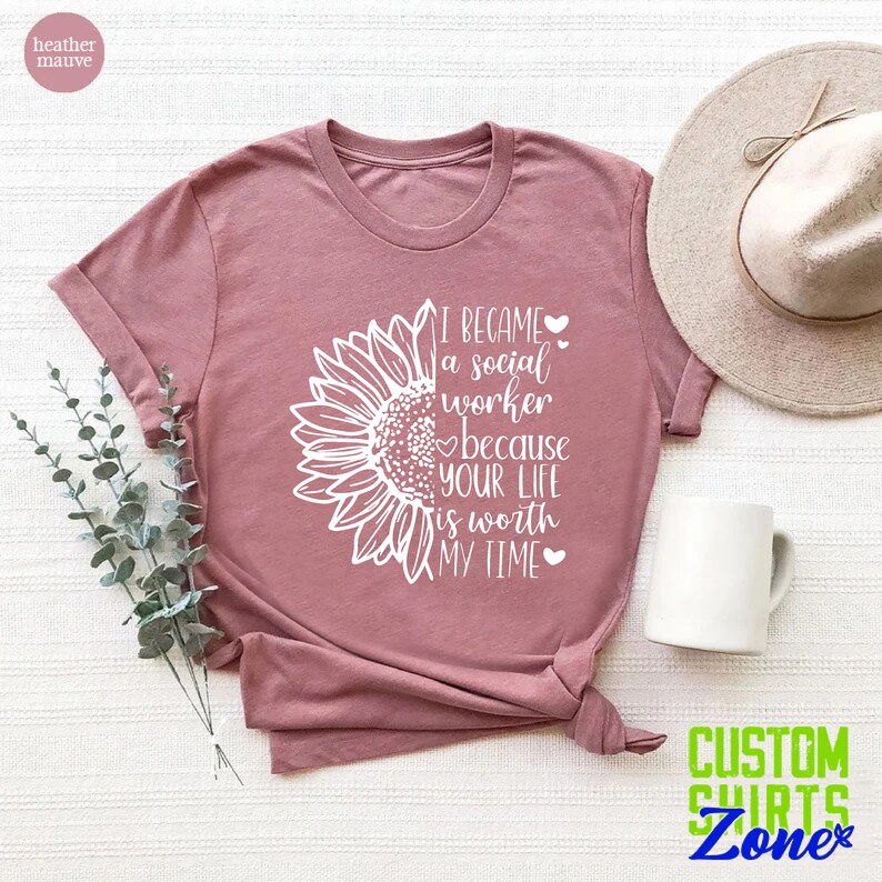May include: A heather mauve t-shirt with a white sunflower graphic and the text "I became a social worker because your life is worth my time".