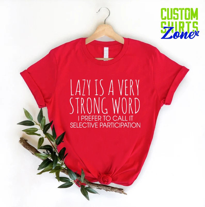 May include: Red t-shirt with white text that reads "Lazy is a very strong word. I prefer to call it selective participation."