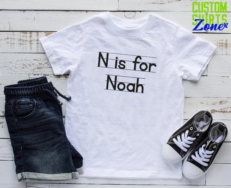 May include: White t-shirt with black text that says "N is for Noah".