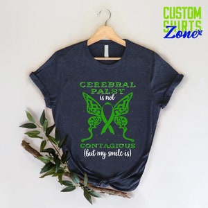 May include: A dark blue t-shirt with a green butterfly design and the text "Cerebral Palsy is not contagious (but my smile is)".