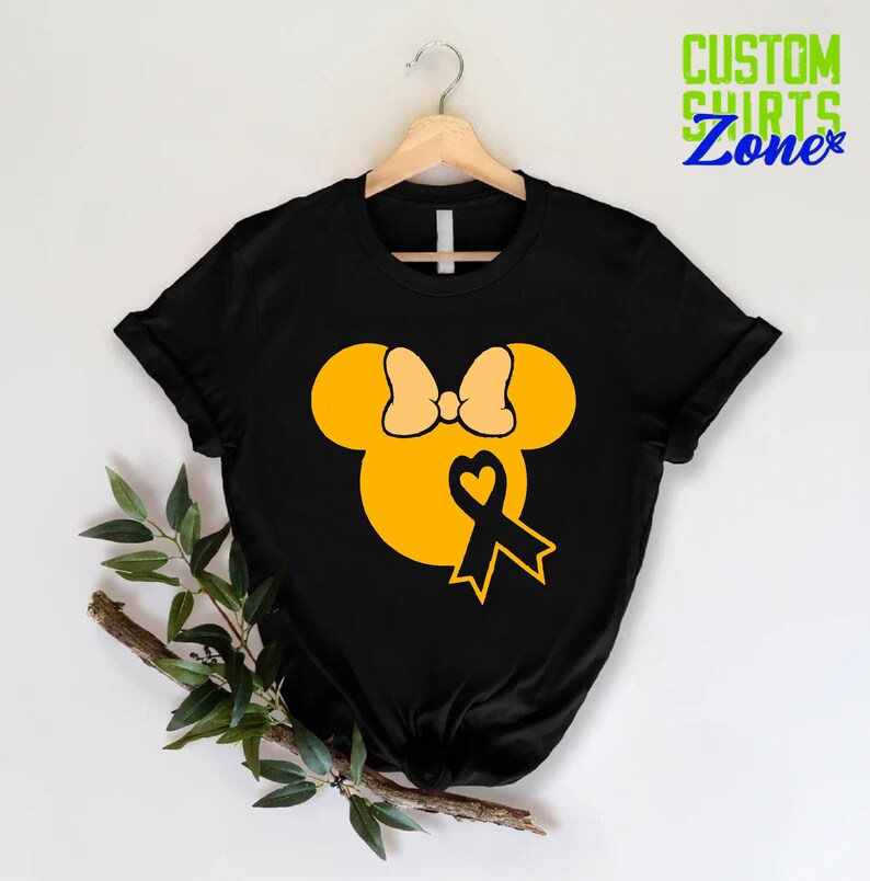 K&ouml;nnte beinhalten: Schwarzes T-Shirt mit einem gelben Mickey-Maus-Kopf-Design. Der Mickey-Maus-Kopf hat eine gelbe Schleife und ein schwarzes Band mit einem Herzen in der Mitte.