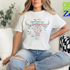 a woman sitting on a couch wearing a t - shirt with a bull's