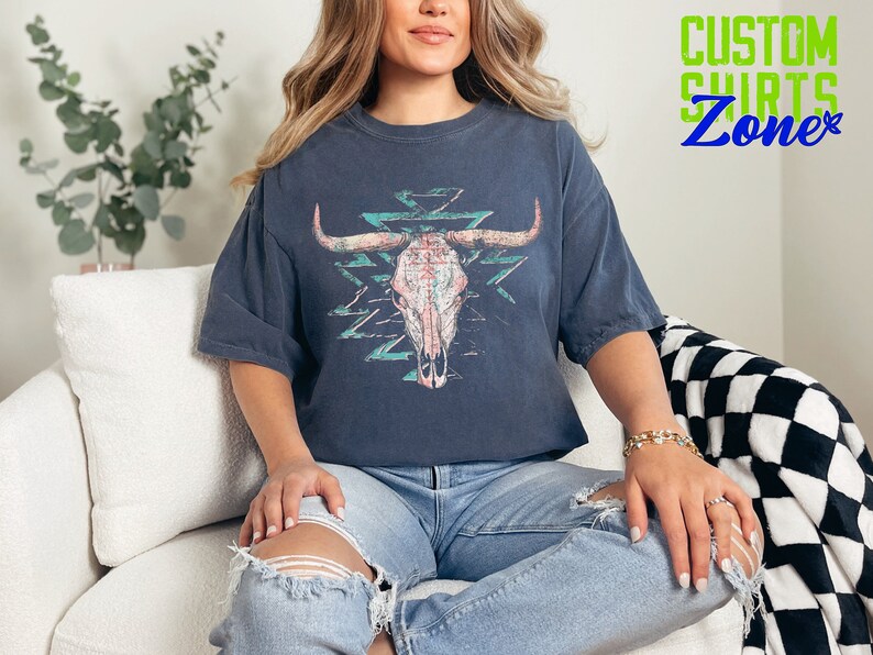 a woman sitting on a couch wearing a t - shirt with a bull's