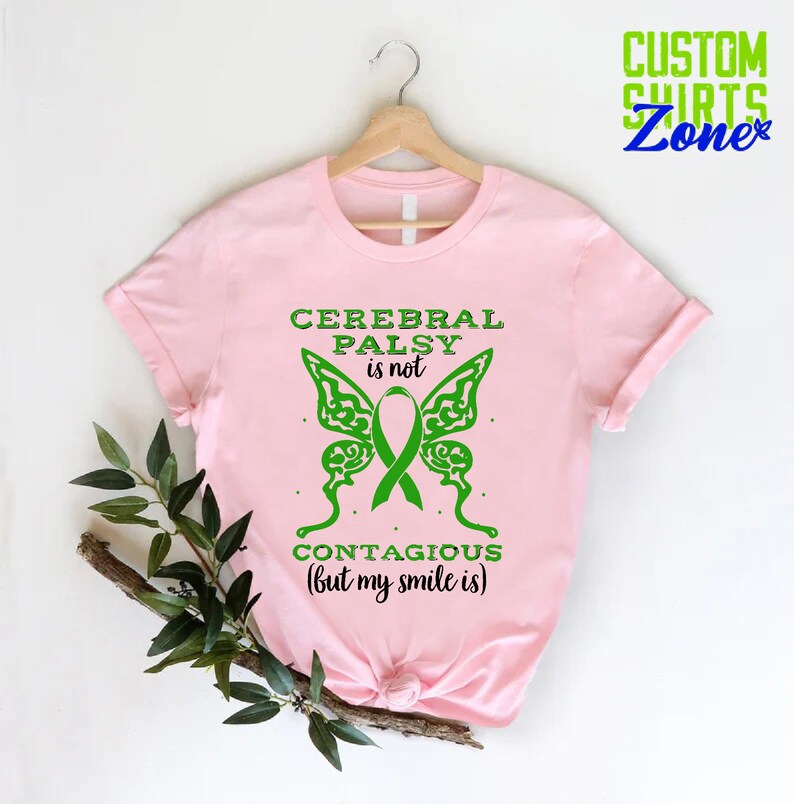 May include: Pink t-shirt with a green butterfly design and the text "Cerebral Palsy is not contagious (but my smile is)".