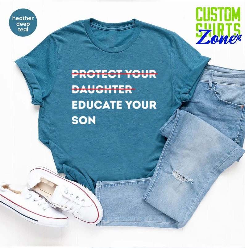 Pu&ograve; includere: Una maglietta blu turchese con la scritta "PROTECT YOUR DAUGHTER EDUCATE YOUR SON" stampata in bianco. Le parole "DAUGHTER" e "PROTECT" sono barrate con una linea rossa.