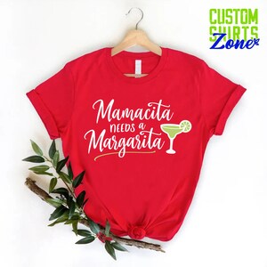May include: Red t-shirt with white text that reads "Mamacita needs a Margarita" and a green margarita glass with a lime wedge.