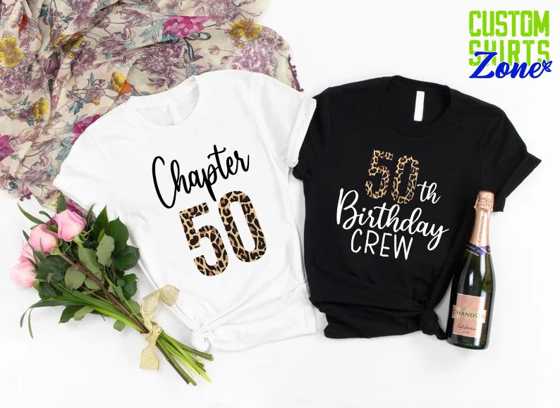 May include: Two t-shirts, one white and one black, with a leopard print design. The white shirt says "Chapter 50" and the black shirt says "50th Birthday Crew".