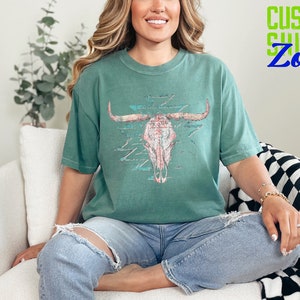 a woman sitting on a couch wearing a green shirt