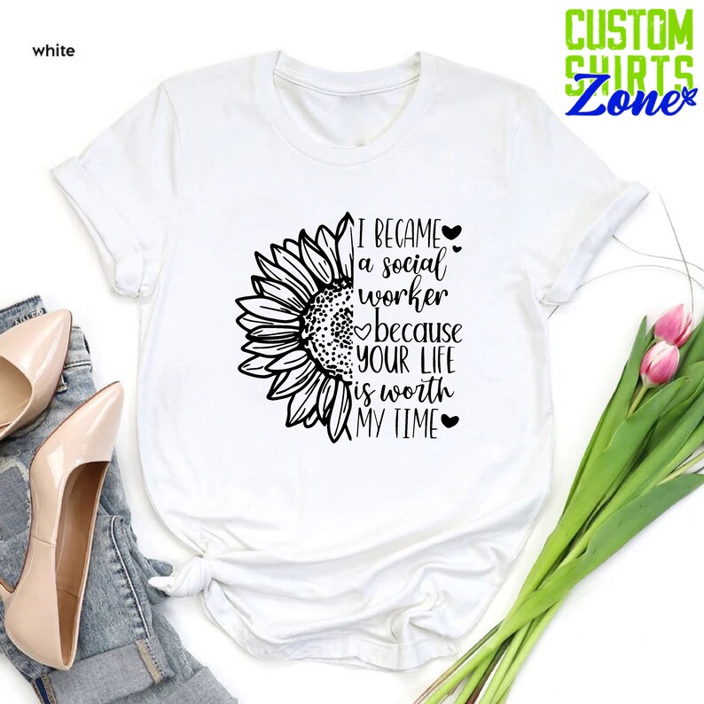 May include: White t-shirt with a black sunflower graphic and the text "I became a social worker because your life is worth my time".
