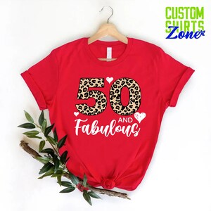 K&ouml;nnte beinhalten: Rotes T-Shirt mit einem Leopardenmuster 50 und dem Text "and Fabulous" in Wei&szlig;.