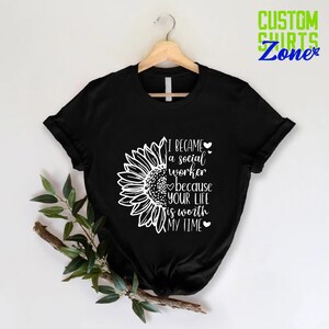May include: Black t-shirt with a white sunflower graphic and the text "I became a social worker because your life is worth my time".