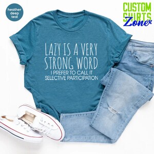 May include: A teal blue t-shirt with the text "LAZY IS A VERY STRONG WORD I PREFER TO CALL IT SELECTIVE PARTICIPATION" printed in white.