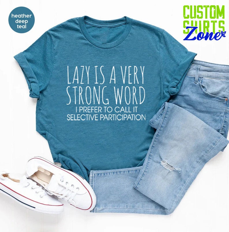May include: A teal blue t-shirt with the text "LAZY IS A VERY STRONG WORD I PREFER TO CALL IT SELECTIVE PARTICIPATION" printed in white.