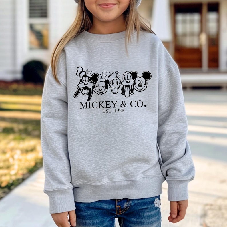 May include: A gray sweatshirt with a black print of Mickey Mouse and his friends. The print says "Mickey & Co. Est. 1928".