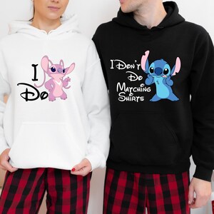 May include: A couple wearing matching hoodies with Stitch from Lilo & Stitch. The woman's hoodie is white with pink Stitch and says "I Do". The man's hoodie is black with blue Stitch and says "I Don't Do Matching Shirts".