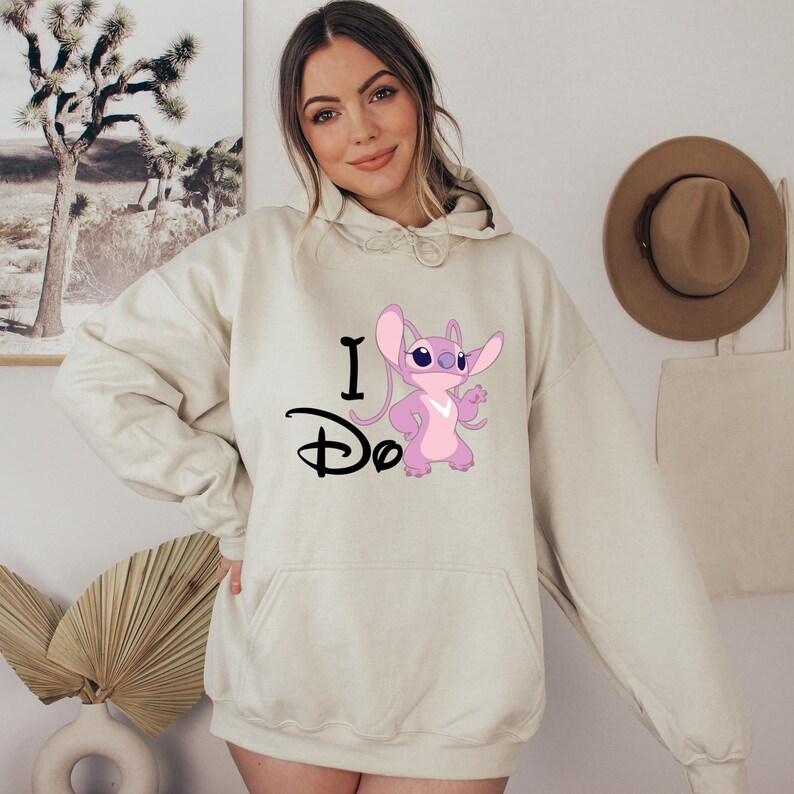 May include: A cream-colored hoodie with a pink Stitch character and the text "I Do" in black.
