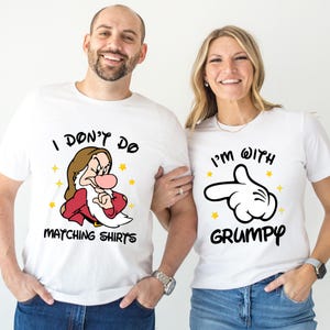 May include: White t-shirts with matching graphics. One shirt features an illustration of Grumpy from Snow White with the text "I DON'T DO MATCHING SHIRTS". The other shirt has a Mickey Mouse hand with the text "I'M WITH GRUMPY".