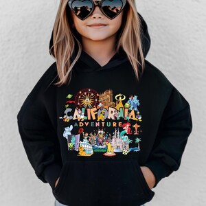 May include: Black hooded sweatshirt with a colorful graphic design featuring the words "CALIFORNIA ADVENTURE" and various cartoon characters and landmarks. The design includes a Ferris wheel, castle, and palm trees.