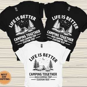 Puede incluir: Tres camisetas, dos negras y una blanca, con un dise&ntilde;o de tem&aacute;tica de camping. El dise&ntilde;o incluye el texto "LIFE IS BETTER" sobre una escena de camping con una tienda de campa&ntilde;a, &aacute;rboles y estrellas. Debajo, se lee "CAMPING TOGETHER" y "2026 CAMPING TRIP - CUSTOM TEXT."