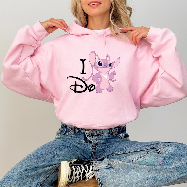 May include: Pink hooded sweatshirt with a cartoon Stitch character and the text "I Do" printed on the front.