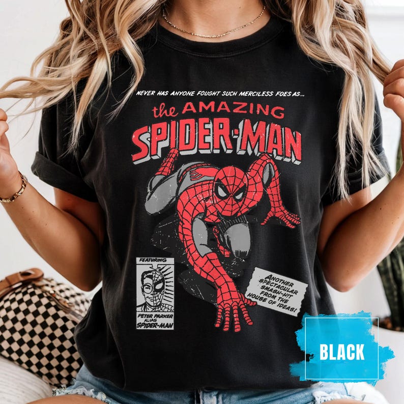 May include: Black t-shirt featuring a vintage comic book style graphic of Spider-Man. The design includes the text "the AMAZING SPIDER-MAN" and other comic book elements. The shirt also has the text "BLACK".