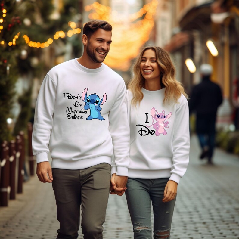May include: A couple wearing white sweatshirts with a blue and pink Stitch character graphic. The man's shirt says "I Don't Do Matching Shirts" and the woman's shirt says "I Do".
