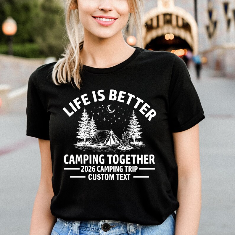 Puede incluir: Camiseta negra con el texto blanco "LIFE IS BETTER CAMPING TOGETHER". El dise&ntilde;o incluye una tienda de campa&ntilde;a, &aacute;rboles, una fogata, una luna creciente y estrellas. Debajo est&aacute; escrito "2026 CAMPING TRIP - CUSTOM TEXT".