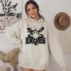 May include: A cream-colored hoodie with a black eagle graphic and the word "EAGLES" printed below it.