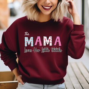 May include: A maroon sweatshirt with the text "This Mama Loves Her Little Stitches" in pink and blue letters with a heart pattern.