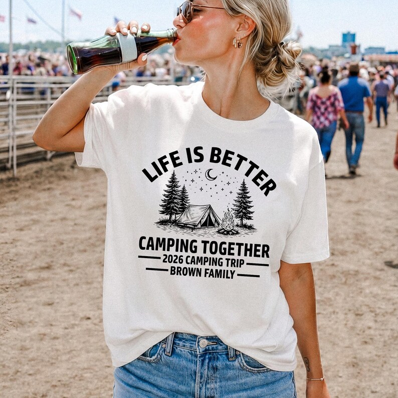 Puede incluir: Camiseta blanca de manga corta con el texto negro "LIFE IS BETTER CAMPING TOGETHER". El dise&ntilde;o incluye una tienda de campa&ntilde;a, &aacute;rboles y una fogata. Debajo est&aacute; escrito "2026 CAMPING TRIP - BROWN FAMILY".