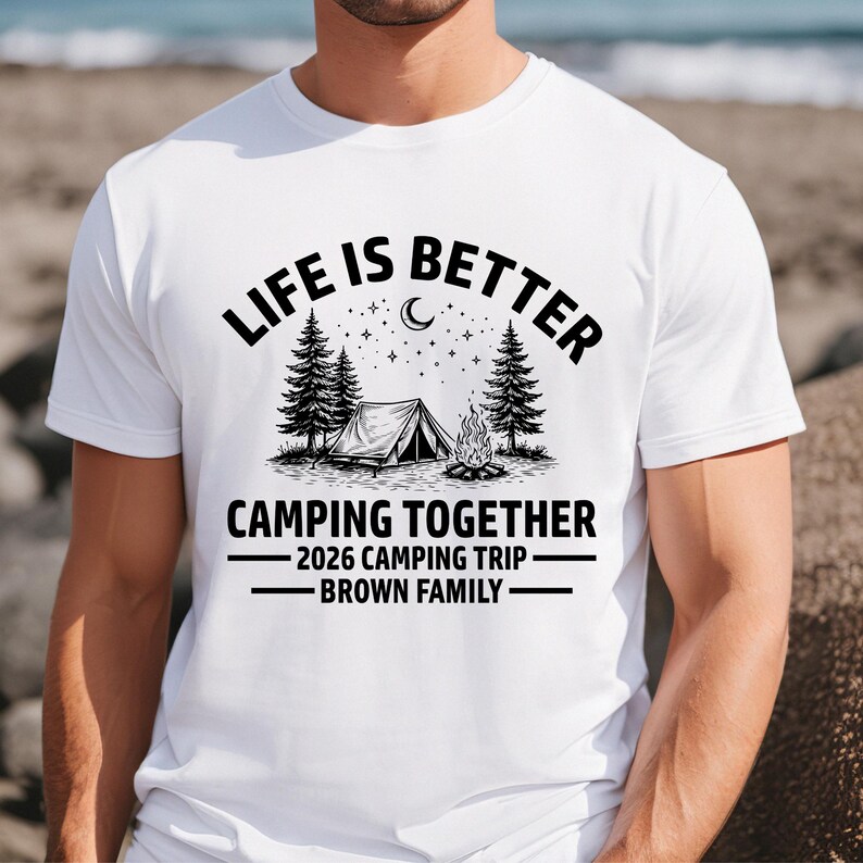 Puede incluir: Camiseta blanca con un dise&ntilde;o de tem&aacute;tica de camping. El dise&ntilde;o incluye el texto "LIFE IS BETTER CAMPING TOGETHER" sobre una ilustraci&oacute;n de una tienda de campa&ntilde;a, &aacute;rboles y una fogata. Debajo est&aacute; "2026 CAMPING TRIP - BROWN FAMILY".