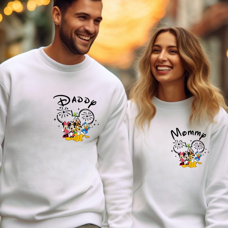 Pode incluir: Su&eacute;teres brancos com um design de Mickey Mouse e as palavras "Daddy" e "Mommy" impressas neles.
