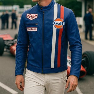 Peut inclure: Veste en cuir bleue avec des rayures de course blanches, rouges et oranges et des écussons de sponsors. La veste a un col montant et une fermeture éclair sur le devant. Le logo Gulf est sur la poitrine. Portée avec un pantalon beige.