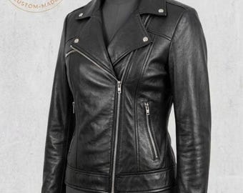 May include: A black leather jacket featuring a notched lapel with silver-tone metal snaps, an asymmetrical front zipper closure, and three zippered pockets on the front. The jacket has long sleeves with cuffs and a fitted silhouette on a mannequin.