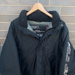 May include: Black puffer jacket with a zip fastening and a white logo that reads "Polo Jeans Co. Ralph Lauren" on the right sleeve.